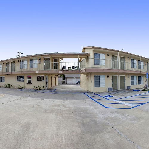 The image shows the exterior of a two-story motel building with parking spaces, including accessible spots. A sign reading "Hotel/Motel" is visible.