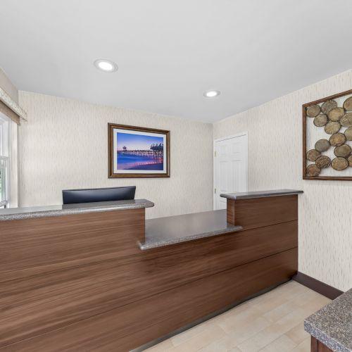 An office reception area with wooden counters, framed photos, and a textured wall display.